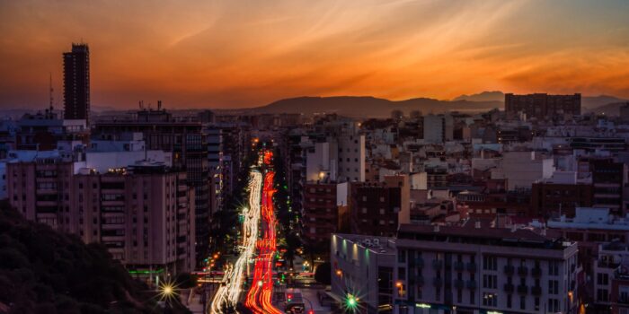 A city with modern buildings and motion light effect under a blue sky during an orange sunset